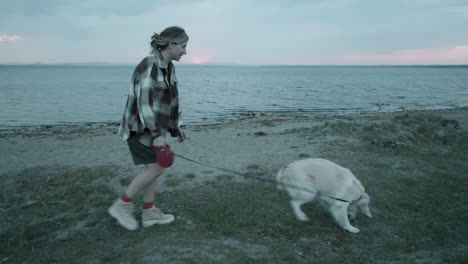 Woman-Walking-with-Dog-on-Lakeside-in-Evening
